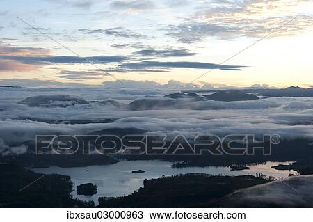 Stock Image - "Sunrise over the mountains, cloudy sky above Maskeliya Reservoir, view from Adam's Peak, Sri Pada, Zentrales Hochland, Dalhousie, Sri Lanka, Asia". Fotosearch