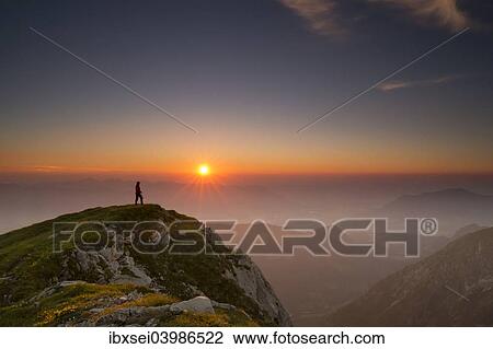 Stock Image - "Sunset with hiker on a summit of the Allgau Alps, Oberstdorf, Bavaria, Germany, Europe". Fotosearch