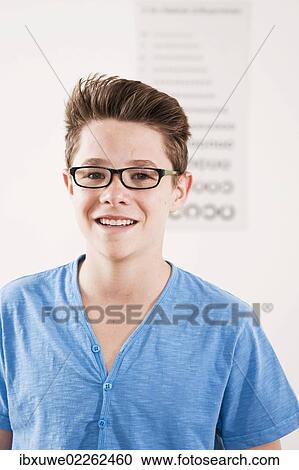 Teenage boy wearing glasses standing in front of an eyesight test View Large Photo Image Stock Image - Teenage boy wearing glasses standing in front of an eyesight test. Fotosearch