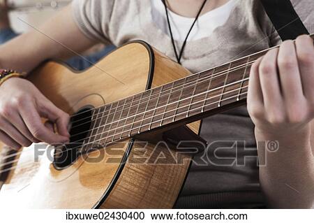 Stock Image - Teenage girl playing the guitar. Fotosearch