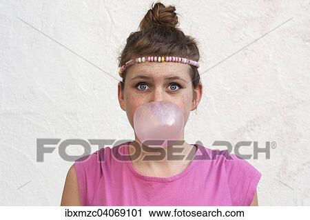 Stock Image - Teenage girl with a gum bubble in front of her face. Fotosearch