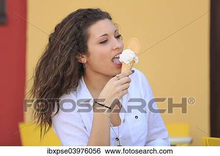 Stock Photograph - "Teenager eating ice cream from a cone on the terrace of an ice cream parlour, Menton, Alpes-Maritimes, Provence-Alpes-Cote d'Azur, France, Europe". Fotosearch