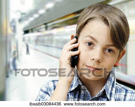 Stock Photograph - "Teenager using a mobile phone in an underground railway station, serious, concentrating". Fotosearch