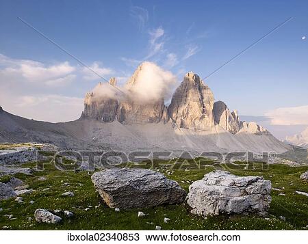 Stock Image - "The peaks of Tre Cime di Lavaredo in clouds at dawn, Dolomiti di Sesto National Park, Sexten Dolomites, Hochpustertal, High Puster Valley, South Tyrol, Italy, Europe". Fotosearch