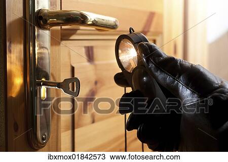Thief using a flashlight to examine a door lock View Large Photo Image Stock Image - Thief using a flashlight to examine a door lock. Fotosearch