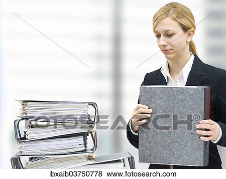 Thoughtful young businesswoman in front of a pile of folders View Large Photo Image Stock Photo - Thoughtful young businesswoman in front of a pile of folders. Fotosearch