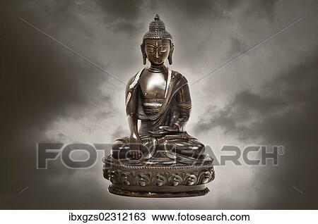 Stock Image - "Tibetan Buddha statue made of bronze, with clouds". Fotosearch