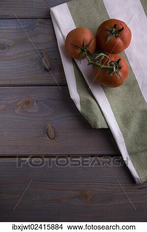 Picture - Tomatoes on a kitchen towel on a wooden background. Fotosearch