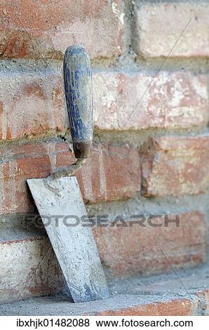 Trowel leaning against a brick wall View Large Photo Image Stock Photo - Trowel leaning against a brick wall. Fotosearch
