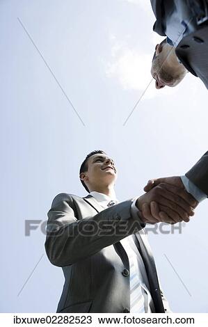 Stock Image - Two businessmen greeting each other with a handshake. Fotosearch