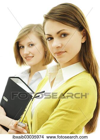 "Two businesswomen, one holding a ring binder" View Large Photo Image Picture - "Two businesswomen, one holding a ring binder". Fotosearch