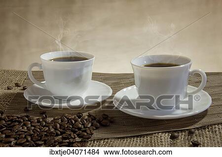 "Two cups of steaming coffee, coffee beans in front" View Large Photo Image Picture - "Two cups of steaming coffee, coffee beans in front". Fotosearch