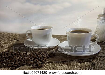 "Two cups of steaming coffee, coffee beans in front" View Large Photo Image Stock Image - "Two cups of steaming coffee, coffee beans in front". Fotosearch