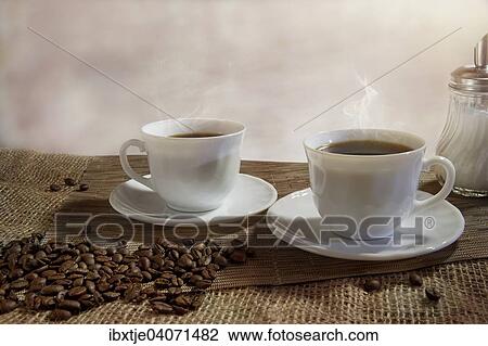 "Two cups of steaming coffee, coffee beans in front" View Large Photo Image Stock Image - "Two cups of steaming coffee, coffee beans in front". Fotosearch