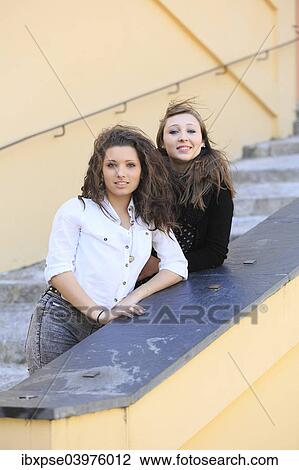 Stock Image - "Two girlfriends, teenagers, posing on a staircase, Menton, Alpes-Maritimes, Provence-Alpes-Cote d'Azur, France, Europe". Fotosearch