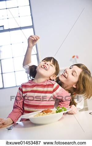 Two girls eating spaghetti together View Large Photo Image Stock Photo - Two girls eating spaghetti together. Fotosearch
