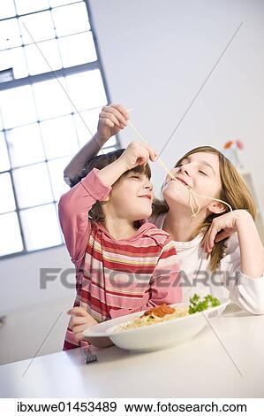 Stock Photo - Two girls eating spaghetti together. Fotosearch