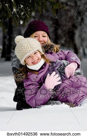 Two girls playing in the snow View Large Photo Image Stock Photograph - Two girls playing in the snow. Fotosearch