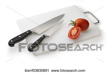 Stock Image - Two knives on a white cutting board with tomatoes. Fotosearch