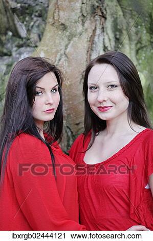 Stock Image - "Two sisters in front of an old tree, portrait". Fotosearch