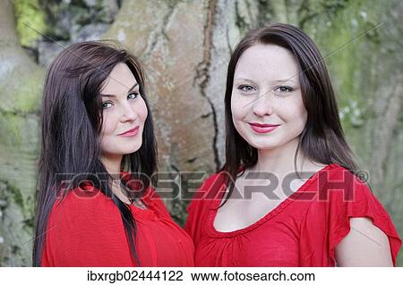 Stock Image - "Two sisters in front of an old tree, portrait". Fotosearch