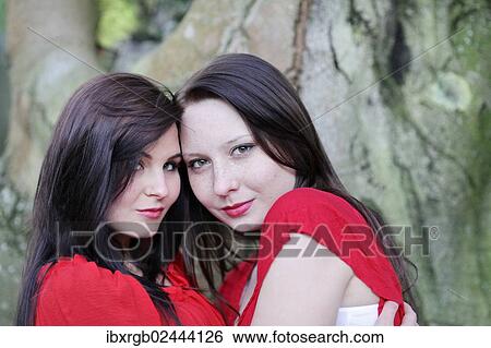 Stock Photograph - "Two sisters in front of an old tree, portrait". Fotosearch