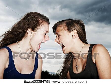 "Two teenage girls screaming at each other, in front of storm clouds" View Large Photo Image Stock Photo - "Two teenage girls screaming at each other, in front of storm clouds". Fotosearch