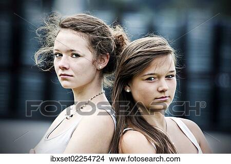 "Two teenage girls standing back to back, looking serious" View Large Photo Image Picture - "Two teenage girls standing back to back, looking serious". Fotosearch