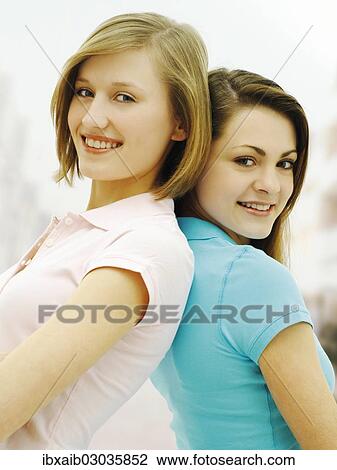 "Two young women, friends, standing back to back" View Large Photo Image Stock Image - "Two young women, friends, standing back to back". Fotosearch