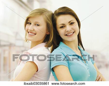 "Two young women, friends, standing back to back" View Large Photo Image Stock Image - "Two young women, friends, standing back to back". Fotosearch