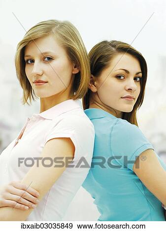Stock Photo - "Two young women, friends, standing back to back". Fotosearch