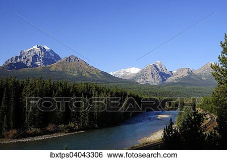 Stock Photograph - "View of the Rocky Mountains across the Bow River and railway tracks, Banff National Park, Alberta, Canada, North America". Fotosearch