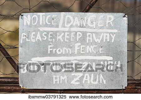 Stock Photography - "Warning sign in English and German on the fence of a predator enclosure, Namibia, Africa". Fotosearch