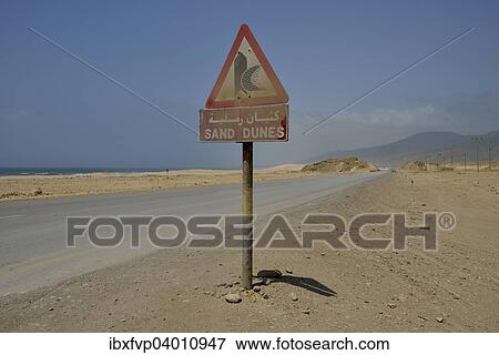 "Warning sign warns of sand dunes, near Mirbat, Dhofar Region, Oman, Asia" View Large Photo Image Stock Photo - "Warning sign warns of sand dunes, near Mirbat, Dhofar Region, Oman, Asia". Fotosearch