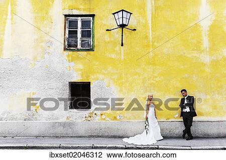 Stock Image - "Wedding, bride and groom in front of a yellow wall". Fotosearch