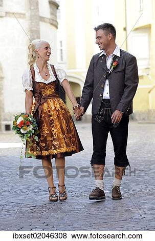 "Wedding, laughing bride and groom in traditional dress walking hand in hand" View Large Photo Image Stock Photo - "Wedding, laughing bride and groom in traditional dress walking hand in hand". Fotosearch