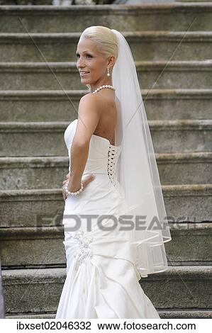 Stock Image - "Wedding, smiling bride standing on a staircase". Fotosearch