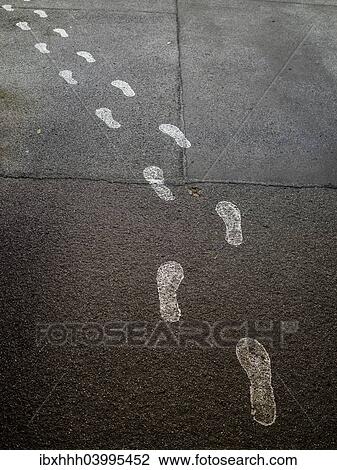 Stock Image - "White footprints on asphalt leading the way, Berlin, Germany, Europe". Fotosearch