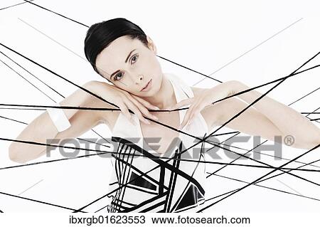 Stock Image - "Woman, 24, dressed in the style of the 60s, standing between spanned threads, symbolic image network". Fotosearch