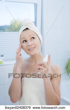 Stock Photo - "Woman, 30+, in the bathroom applying facial care". Fotosearch