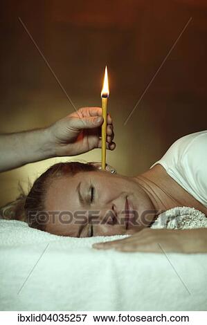 Stock Photo - "Woman, 44 years, is being treated with an ear candle". Fotosearch