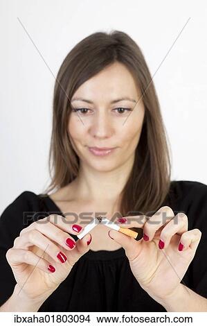 Picture - Woman breaking a cigarette. Fotosearch