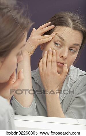 Woman checking ageing skin in the mirror View Large Photo Image Stock Photography - Woman checking ageing skin in the mirror. Fotosearch