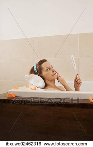 Woman checking her expression lines while bathing View Large Photo Image Stock Photograph - Woman checking her expression lines while bathing. Fotosearch