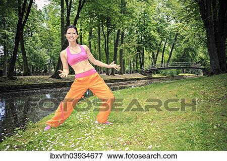Stock Photo - Woman dancing zumba in a park. Fotosearch