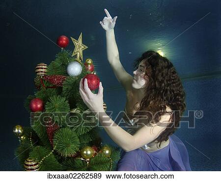 Stock Photo - "Woman decorating Christmas tree under water in a pool, Odessa, Ukraine, Eastern Europe, Europe". Fotosearch