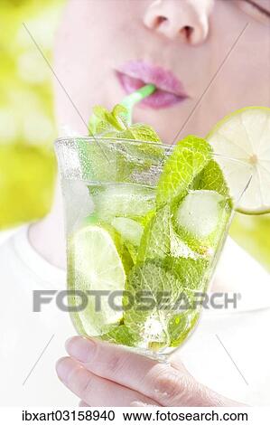 Stock Image - Woman drinking a Hugo cocktail with lime and mint. Fotosearch