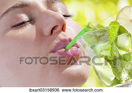 Stock Photograph - Woman drinking a Hugo cocktail with lime and mint. Fotosearch