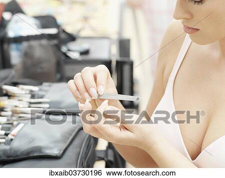 Woman filing her nails View Large Photo Image Stock Photograph - Woman filing her nails. Fotosearch