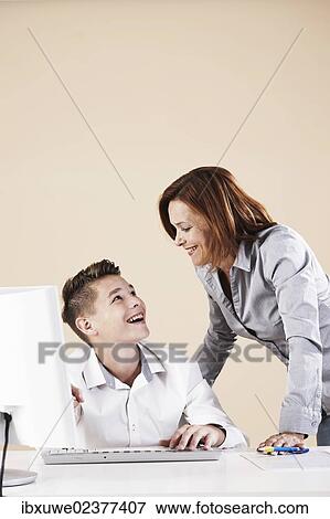 Woman helping a boy on a computer View Large Photo Image Stock Photo - Woman helping a boy on a computer. Fotosearch